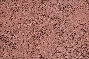 Dark pink plaster rough masonry cement house facade wall closeup as background