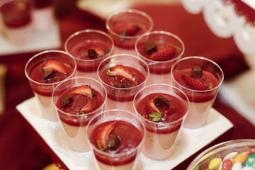 stylish desserts with strawberry, candy bar with sweets at luxury wedding reception. catering at restaurant. cupcakes  macaroons on table. space for text