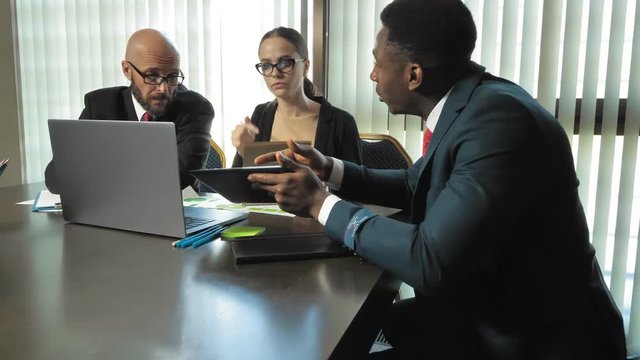 Multiracial businessmen discuss new ideas and plans of the company in the conference hall in slow motion