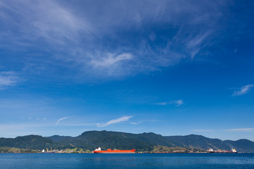 Naklejka na ściany i meble Panoramic view with sea, mountain and blue sky on sunny summer day and a port with ships in Ilha Bela on the coast of São Paulo, Brazil.