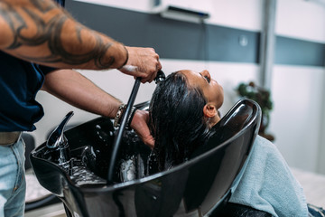 Professional hairstylist washing clients hair.