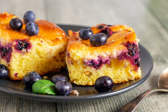 Two Pieces Of Blueberry Cake On A Dark Saucer.