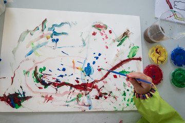 Young child creating a colourful abstract painting