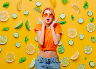 Young style girl with orange glasses on background with lemons and cucumbers. Clothes in 1980s style