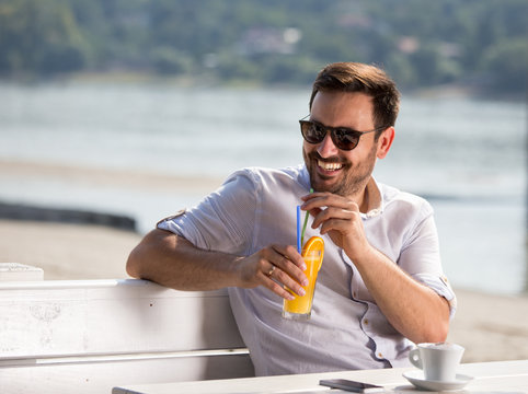 Smiling man enjoying in cafe in beach