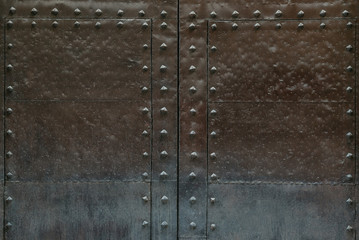 An ancient scratched metal door with metal rivets in Spain. Chocolate color