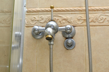 Bathroom faucet on a beige tiled bathroom wall
