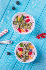 Whipped quark mousse with raspberries, blueberries, red currant and fizalis on a blue background. Top view, free space