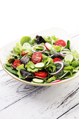 bowl of salad with vegetables and greens, with tomato, cucumber and onions