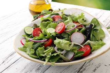 bowl of salad with vegetables and greens, with tomato, cucumber and onions