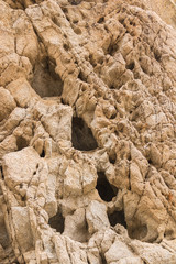 Close up of desert rock wall with deep dark holes and cracks on the surface