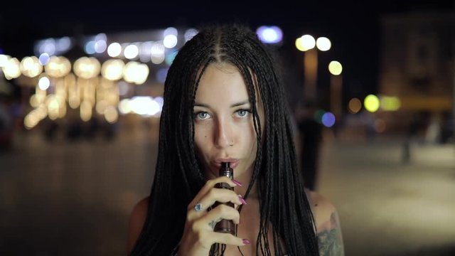 Woman smoking e-cigarette at the night city