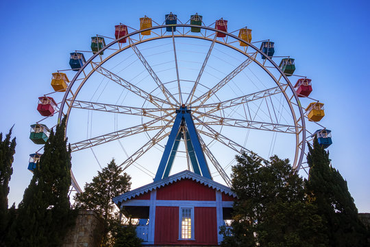 Ferris wheel with colorful swings at sunsets with blue sky in front view