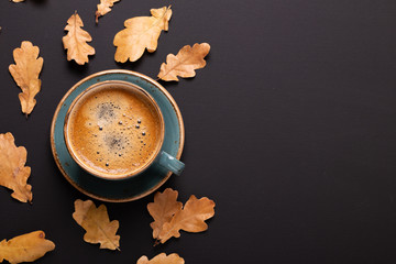 Autumn composition. Cup of coffee and dry leaves on black background. Top view. Flat lay.
