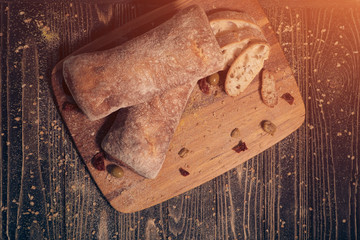 delicious white ciabatta slices with olives on wood;