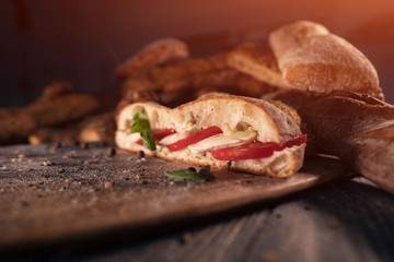 fresh sandwich with tomato, basil and mozzarella on wood;