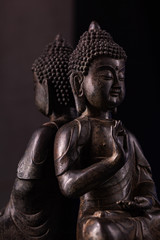 Buddha Shakyamuni's figure in a meditation pose - vitarka mudra. The old statue brown color made of metal on a dark background.