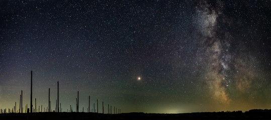 High posts in the field against the background of the star sky and the Milky Way with a bright star in the center.