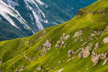 Fototapeta premium Green grass hillside with hiking paths and rocks