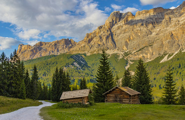 Fototapeta na wymiar Two sheds near the gravel road and forest with rock mountains and hillsides in background