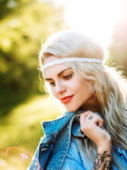 Portrait of a beautiful girl in a blue dress with a headache in a field at sunset in summer. Casual summer clothes. Close-up