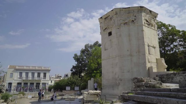 Tourists milling around White Marble Tower in Ruins around the Roman Agora in Athens, Greece