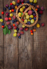 variety of plums on wooden surface