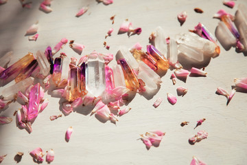 Colorful quartz crystals with pink rose leaves on wooden structure, flat lay background   - 219048017