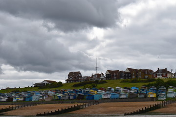 View of the sandy beach and painted wooden beach huts at Whitstable in Kent in south east England....