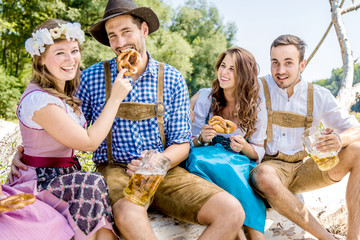 Freunde in trachtenmode entschpannen an der Isar