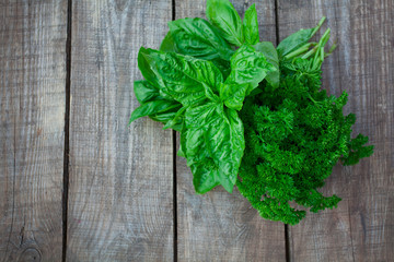 bunch of parsley and basil on wooden surface