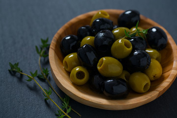 olives in a wooden bowl on black surface