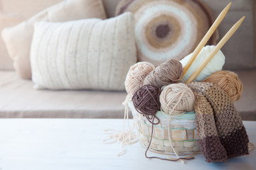Neutral beige, brown, white yarn in a wicker basket. White background. Aged wood.