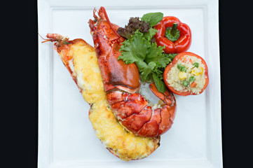 Close up lobster bake with cheese sliced in half serviced with fire rice in tomato.