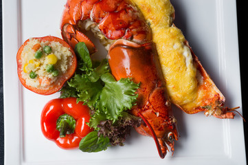Close up lobster bake with cheese sliced in half serviced with fire rice in tomato.