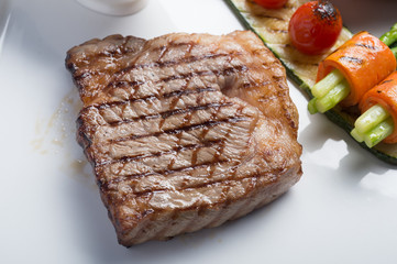 Close up Hida beef steak with grilled tomato, carrot, cucumber and asparagus on white plate