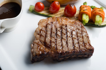 Close up Hida beef steak with grilled tomato, carrot, cucumber and asparagus on white plate