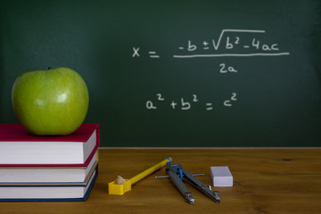 Back To School, una manzana verde sobre una pila de libros frente a una pizarra