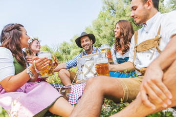 Oktoberfest Freunde in Lederhosen und Dirndl trinken Bier an der Isar