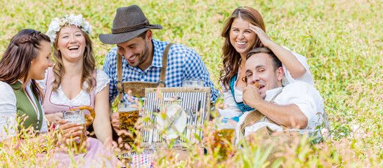Oktoberfest Freunde in Lederhosen und Dirndl trinken Bier an der Isar