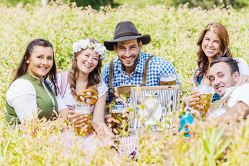 Oktoberfest Freunde in Lederhosen und Dirndl trinken Bier an der Isar