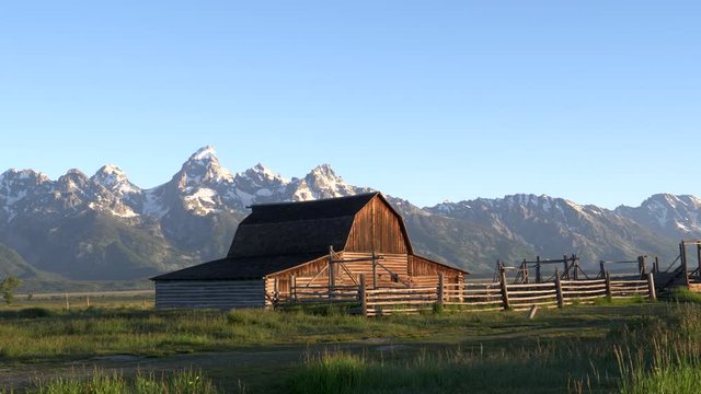 a panning left shot of grand teton and a barn at sunrise in grand teton national park of wyoming, usa