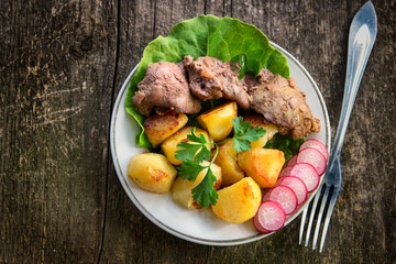 Chicken liver with fried potatoes, lettuce leaves and sliced radish