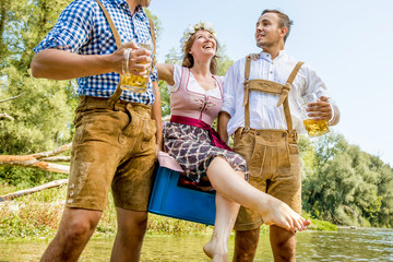 Oktoberfest Freunde in Lederhosen und Dirndl trinken Bier an der Isar