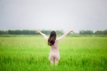 Naklejka na ściany i meble Girl, standing, looking at a green field , Beautiful natural background