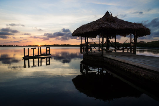 Sun setting at the calm lagoon behind Utila sign and dock, Utila, Honduras, Central America
