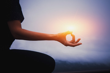 Close up hands. Woman practices yoga and meditates on the mountain.