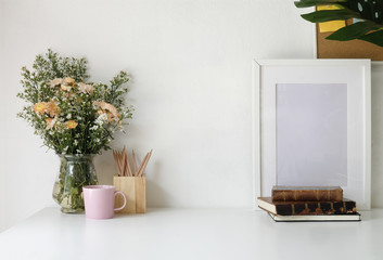 Stylish workspace with poster, book and flower bouquet. Workplace desk and copy space.