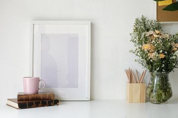 Stylish workspace with poster, book and flower bouquet. Workplace desk and copy space.