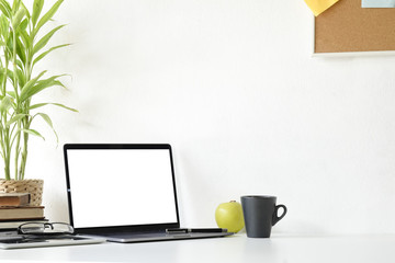 Mockup laptop computer,book and office supplies on white desk.